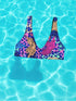 Psychedelic animal print bikini top with multicolor tiger pattern in neon pink, purple, orange, and blue, made of stretchy recycled fabric with wide shoulder straps and scoop neckline.