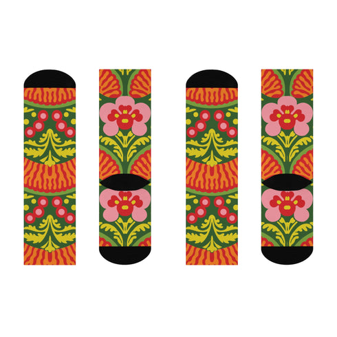 Mid-calf crew sock with a bold retro 70s maximalist botanical print. A deep green base is packed with golden yellow fern-like leaves, pink folk-style flowers with red centers, and clusters of round red and pink berries. Orange and red shell motifs with wavy stripes band the cuff and lower sock. The toe and heel are solid black. The fabric is a soft, stretchy printed knit, made as a one-size unisex statement sock for maximalist and dopamine dressing looks.