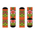 Mid-calf crew sock with a bold retro 70s maximalist botanical print. A deep green base is packed with golden yellow fern-like leaves, pink folk-style flowers with red centers, and clusters of round red and pink berries. Orange and red shell motifs with wavy stripes band the cuff and lower sock. The toe and heel are solid black. The fabric is a soft, stretchy printed knit, made as a one-size unisex statement sock for maximalist and dopamine dressing looks.