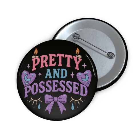 Glossy black pinback button featuring pastel-style text that reads “Pretty and Possessed” with a bow, candles, hearts, and sparkles.
