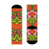 Mid-calf crew sock with a bold retro 70s maximalist botanical print. A deep green base is packed with golden yellow fern-like leaves, pink folk-style flowers with red centers, and clusters of round red and pink berries. Orange and red shell motifs with wavy stripes band the cuff and lower sock. The toe and heel are solid black. The fabric is a soft, stretchy printed knit, made as a one-size unisex statement sock for maximalist and dopamine dressing looks.