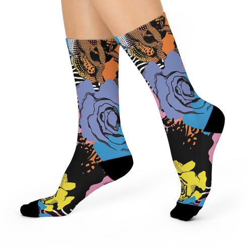 Colorful crew-length socks with a vibrant floral pop-art collage design, featuring abstract roses in yellow, lavender, pink, and orange tones, polka dots, and zebra stripes on a black background.
