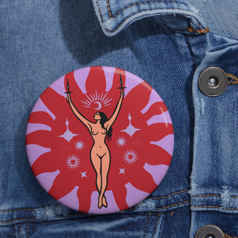Circular pin featuring a nude goddess figure in gold against a red sunburst pattern on lavender background, with moon and star details