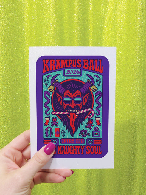 A vertical 5x7 inch folded greeting card featuring a detailed, psychedelic illustration of the folklore figure Krampus for a New Year celebration. The card stock has a shimmering pearlescent finish that reflects light, creating a glowing effect on the purple and teal artwork. The design mimics a vintage event poster reading "Krampus Ball 2026" and "Entry Fee: One Naughty Soul" in retro fonts. Krampus is depicted with large horns, sunglasses, and a long tongue holding a candy cane.