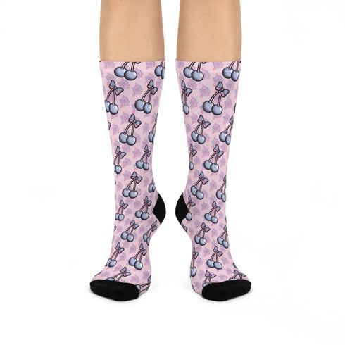Pink crew socks with playful cherry and bow print. Retro-inspired design with a coquette aesthetic against a soft pink background. Black heel and toe accents.