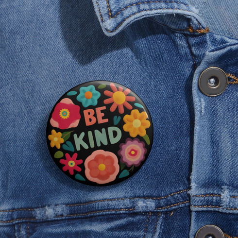 Bold "BE KIND" pinback button featuring vibrant psychedelic flowers in hot pink, teal, yellow, and orange on black background. Retro 70s-inspired typography in coral and mint green surrounded by colorful blooms. Statement activist accessory perfect for punk fashion, protest wear, and battle vests. Glossy UV-resistant finish with safety pin backing available in 2" and 3" sizes.