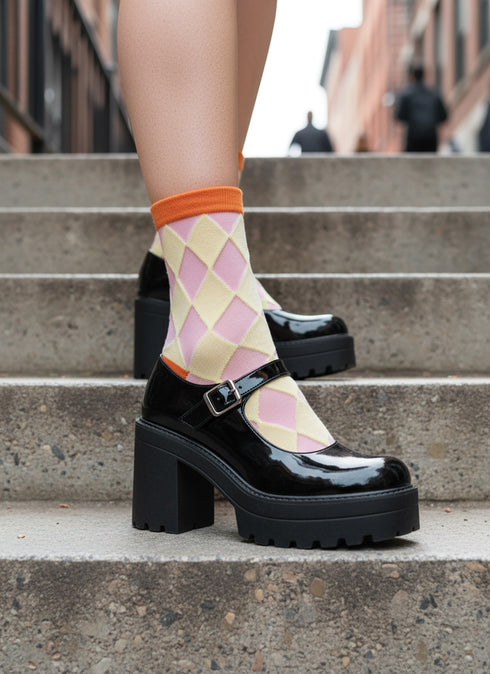 A pair of black chunky heels with a platform sole, worn by a person standing on a set of stairs.