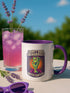 White ceramic coffee mug with red handle and interior, featuring a bold design of a zombie hand holding a coffee cup with the text “I Don’t Rise, I Resurrect With Coffee” in white and purple, accented with a neon green hand and orange sunburst background.