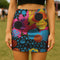 A woman wearing a colorful, patterned mini skirt stands in a grassy field.