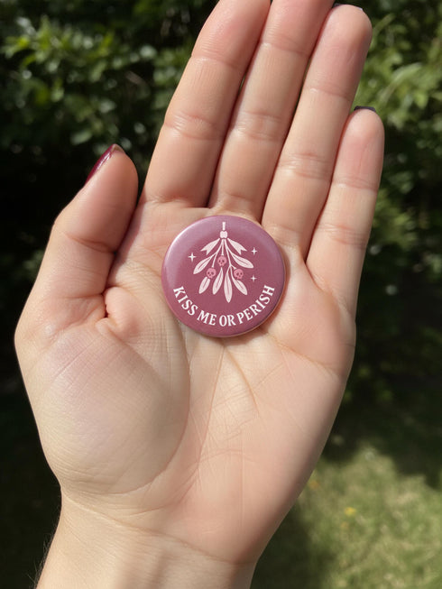 Set of 4 1.75 inch round pastel goth holiday pinback buttons. 1: Light pink with Baphomet head in wreath reading Merry Hexmas Hail Yourself. 2: Dark mauve with skull mistletoe reading Kiss Me or Perish. 3: Dark mauve with coffin stocking and black cat reading All I Want is Doom. 4: Light pink with cute Baphomet holding a sack reading Naughty on Purpose. All feature durable tinplate construction, high gloss laminate finish, and a secure metal safety pin back.