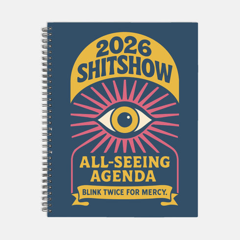 A hardcover spiral planner for 2026 with a dark blue cover and retro 70s style graphics. The title reads "2026 SHITSHOW All-Seeing Agenda" in bold yellow and pink text. Below the title is a large, stylized all-seeing eye with pink rays emanating from it. At the bottom, a pink ribbon contains the text "BLINK TWICE FOR MERCY." The back cover is also dark blue with a yellow sun graphic and the text "Plans bloom. Deadlines hum. I write, I wander, then get it done. Keep receipts. Keep grace.