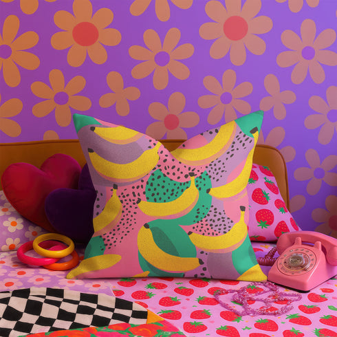 Colorful square pillow cover featuring a bold banana print in yellow, pink, green, purple, and black. The print appears on both sides and is made of luxe polyester with a linen-like texture. Hidden zipper closure. Available in two sizes: 22x22 inches and 18x18 inches. Designed for bright, dopamine-style, maximalist home decor.