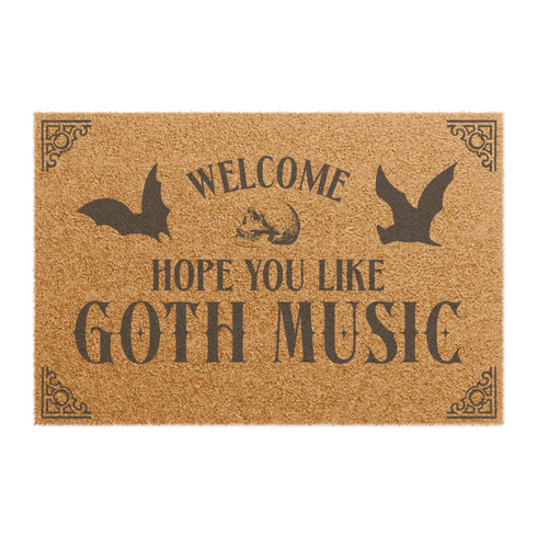 Tan coir doormat featuring "Welcome, Hope You Like Goth Music" in black text, with bat and skull imagery and gothic-style corner decorations.