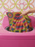 A square faux embroidery pillow featuring a brightly colored maximalist design against a mustard yellow background. In the center stands a stylized, furry Bigfoot or Sasquatch figure rendered in vibrant layers of pink, orange, blue, and lime green with a blue face and yellow eyes. The central creature is surrounded by large, detailed symmetrical pink and blue flowers and leaves. The flat printed fabric creates a highly realistic optical illusion of dimensional crewel embroidery stitches.