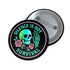 Round enamel pinback button available in 2.5″ or 3″ sizes with a black base and high-gloss finish. The design features neon green and blue gradient skull in the center, pastel pink roses and green leaves below, and mint skeleton hand on the right side. Arched text reads “SILENCE IS NOT SURVIVAL” in teal block letters. Shown styled on a denim jacket, held in hand against bright yellow backdrop, placed in a candy heart flat lay, and propped on pavement in front of graffiti wall.