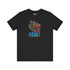 Black t-shirt with vibrant multicolored patterned raised fist graphic and blue "RESIST" text underneath. Rainbow activist protest shirt with psychedelic design elements on cotton-polyester blend.