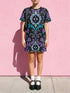 Cotton t-shirt dressA short-sleeve structured t-shirt dress with a black background. The dress features a bold, vertically stacked repeating graphic print. The design includes intricate damask patterns in teal and grey, purple roses with teal leaves, and a central evil eye motif set inside an ornate frame with small four-point stars. The heavyweight fabric holds a clean, straight cut above the knee with zero drape, maintaining a sculptural, slightly boxy silhouette.