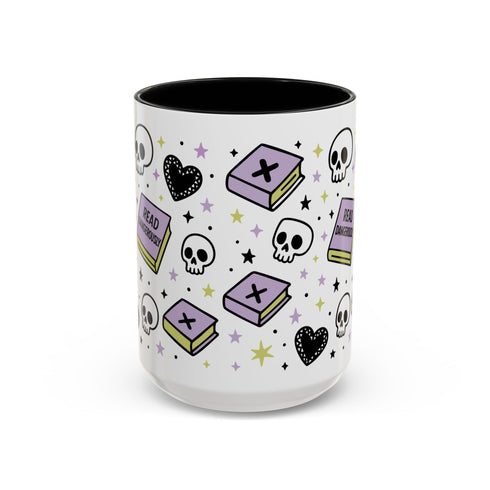 The Gothic Read Dangerously Mug (11, 15oz) features a glossy ceramic finish with pastel book, skull, heart, and star illustrations. Books labeled READ and CURIOUS plus black, purple, and yellow accents add a charming gothic vibe.