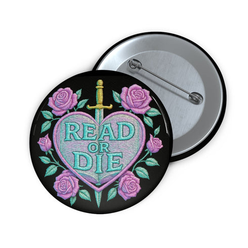 Glossy black pinback button featuring embroidered-style artwork of a pastel purple heart that reads “Read or Die” pierced by a sword and surrounded by roses; shown on books, graffiti, and lace backgrounds.