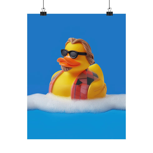 A quirky art print of a rubber duck styled after The Dude from The Big Lebowski, complete with a goatee, sunglasses, and plaid bathrobe. The duck lounges in bubbles, framed in a glossy red frame, with a manicured hand adjusting it against a monochromatic red backdrop.