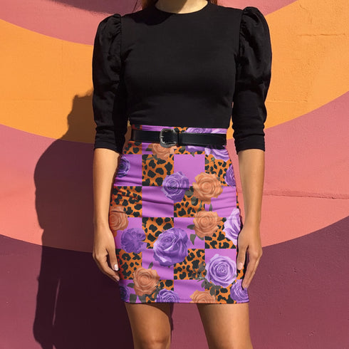 A woman wearing a black top and a short skirt with a floral pattern, standing in front of a colorful wall.