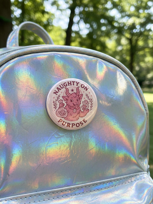 Set of 4 1.75 inch round pastel goth holiday pinback buttons. 1: Light pink with Baphomet head in wreath reading Merry Hexmas Hail Yourself. 2: Dark mauve with skull mistletoe reading Kiss Me or Perish. 3: Dark mauve with coffin stocking and black cat reading All I Want is Doom. 4: Light pink with cute Baphomet holding a sack reading Naughty on Purpose. All feature durable tinplate construction, high gloss laminate finish, and a secure metal safety pin back.