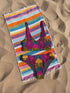 Tropical tiger print bikini bottom with vibrant pink, yellow, and teal psychedelic design. Mid-rise cut with cheeky coverage, double-layered fabric, UPF 50+, and soft, stretchy recycled polyester-spandex blend.