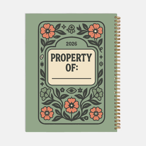 A sage green hardcover spiral planner for 2026 with the title "The 2026 Planner of Controlled Chaos" in a funky, retro 70s-style font. The cover features a groovy illustration of orange and pink flowers in a vase, with one flower depicted as an eyeball. The text reads "Bloom where you're planted. Or just wilt artfully." and "Notes from the Void." The planner has a gold metal wire-o binding. The back cover shows a decorative floral frame with a "Property Of" section