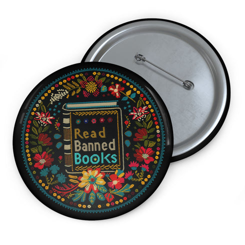 Round black pinback button with vibrant Mexican folk art-inspired embroidery design featuring red, yellow, blue and teal flowers surrounding a gold book spine with "Read Banned Books" text. Literary protest accessory with glossy finish and safety pin backing, available in 2" and 3" sizes.