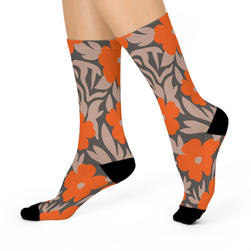 Colorful mid-calf crew socks featuring a bold orange hibiscus floral pattern layered over wavy zebra stripes in taupe and gray, with black heels and toes.