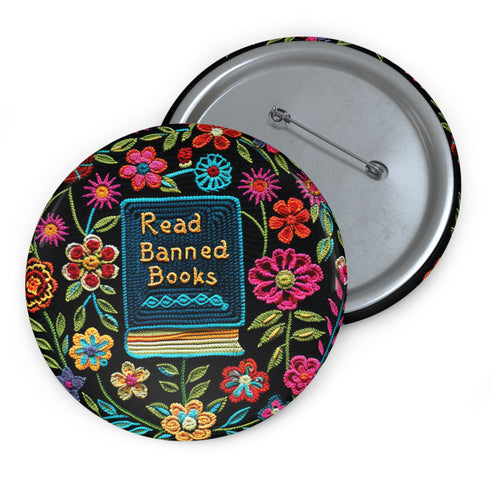 Round pinback button featuring a teal book with "Read Banned Books" in gold lettering on black background, surrounded by vibrant embroidery-style flowers in pink, orange, and blue. Literary protest pin with glossy finish and safety pin backing, available in 2" and 3" sizes for bookish fashion statements.