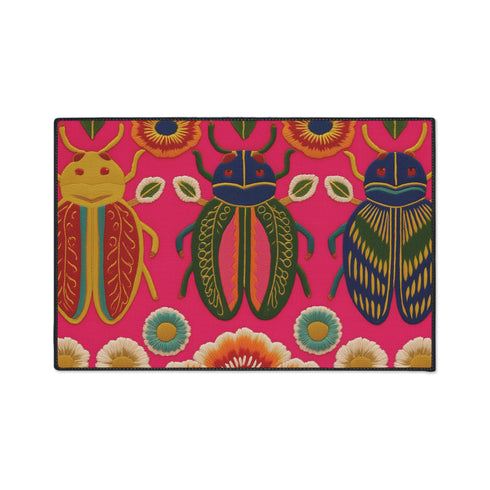 A rectangular doormat featuring a vibrant hot pink background with a high-fidelity tapestry-style print of three large, detailed beetles. The central beetle is emerald green and gold with navy accents, flanked by two side-profile beetles in ochre and deep blue. Stylized teal and yellow sunburst flowers and small sage green leaves are scattered throughout the design. The mat has a sleek black-trimmed edge and a visible flat, durable polyester texture mimicking intricate needlework.