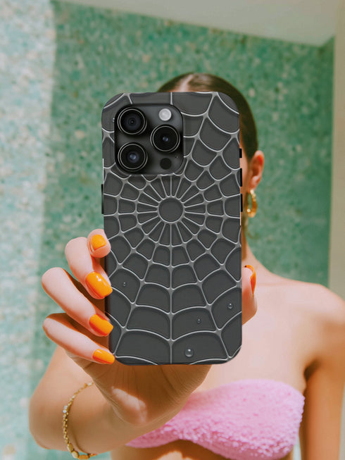 A person is taking a selfie with a spider web-patterned phone case, holding the phone up to the camera.