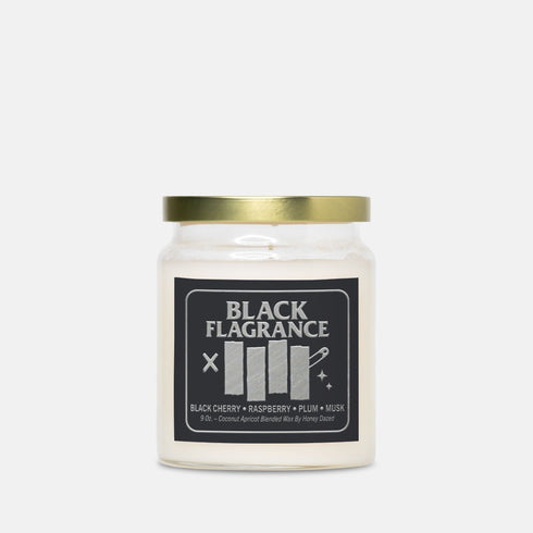 A 9-ounce hand-poured candle in a clear, cylindrical glass jar with a slight taper at the base. The wax is a creamy, solid off-white color, filling the jar to just below the rim where a single white cotton wick is centered. The label features the words "BLACK FLAGRANCE" in a bold, white, sans-serif font. Below this, a stylized graphic mimics a famous punk band logo with four vertical white bars. The candle is topped with a shiny, metallic gold-colored lid.