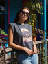 A garment dyed charcoal grey women's muscle tee featuring a slightly cropped boxy fit with structured shoulders and a wide rib collar. The front displays a retro 70s psychedelic graphic printed in purple, orange, and yellow. The text reads MY BODY MY CHOICE surrounding a central eye motif with a radial sunburst, framed by symmetrical mystical swirls and four point stars. The vintage style cotton shirt offers a faded aesthetic, presented on its own without background lifestyle elements.