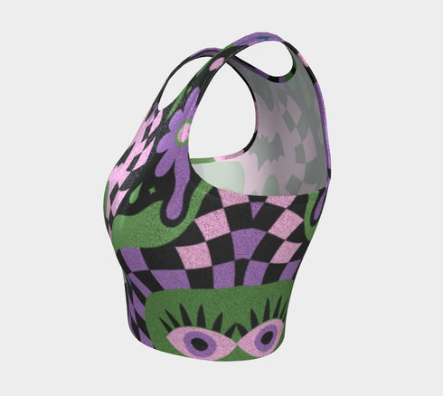 A close-up view of a sleeveless performance knit crop top featuring a vibrant pastel goth all-over print on a solid black background. The repeating pattern includes large black vampire bats flying over dripping, melted slime shapes in neon green. Wavy, warped checkerboard patterns in pastel pink, light purple, and black weave through the design. The graphic is finished with stylized, oversized pastel floral motifs and large open eyeballs staring outward.