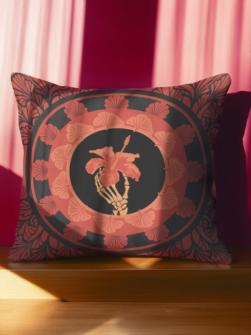 Square pillow cover featuring a golden skeleton hand holding a coral hibiscus flower, surrounded by fan-shaped coral motifs on a black background in an Art Nouveau style.