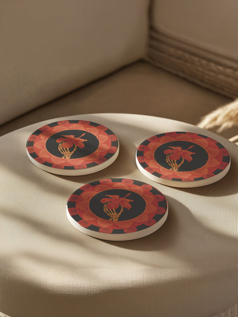 Round ceramic coaster featuring a skeleton hand holding a coral hibiscus flower, surrounded by art deco fan patterns in coral and black