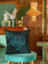 Square woven pillow featuring fierce turquoise tiger with bared fangs against black background surrounded by neon jungle leaves. Textured tapestry creates vibrant midnight tiki decor perfect for rockabilly, maximalist room styling.