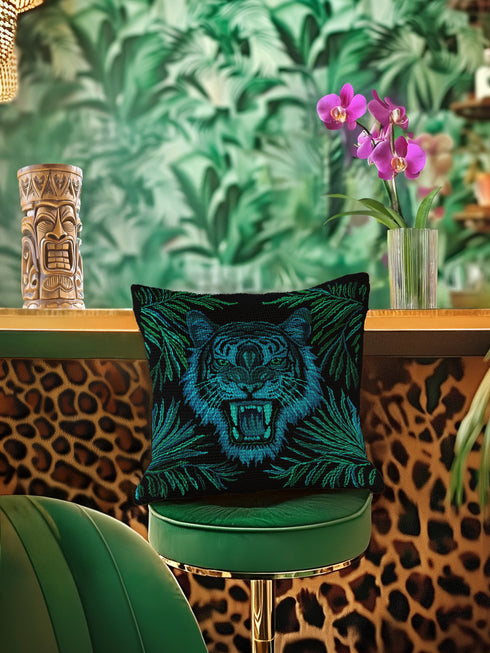 Square woven pillow featuring fierce turquoise tiger with bared fangs against black background surrounded by neon jungle leaves. Textured tapestry creates vibrant midnight tiki decor perfect for rockabilly, maximalist room styling.