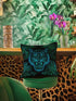 Square woven pillow featuring fierce turquoise tiger with bared fangs against black background surrounded by neon jungle leaves. Textured tapestry creates vibrant midnight tiki decor perfect for rockabilly, maximalist room styling.