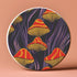 Round ceramic coaster featuring orange and yellow mushrooms with striped caps against a dark background with flowing purple lines in a psychedelic 70s style