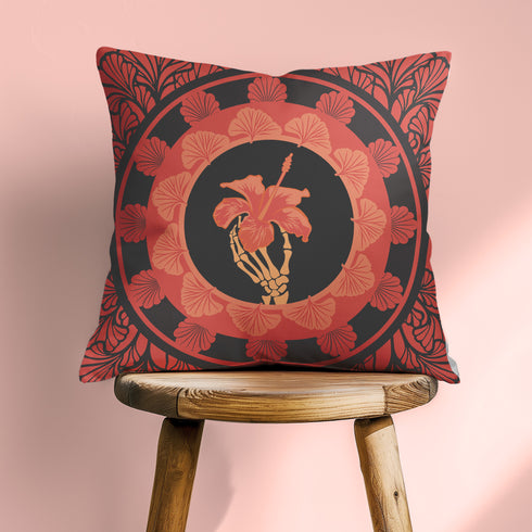 Square pillow cover featuring a golden skeleton hand holding a coral hibiscus flower, surrounded by fan-shaped coral motifs on a black background in an Art Nouveau style.
