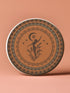 Round ceramic coaster featuring a silhouetted dancing figure reaching for a crescent moon, surrounded by concentric rings of stars and botanical patterns in terracotta and umber tones