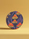Round ceramic coaster featuring orange and yellow mushrooms with striped caps against a dark background with flowing purple lines in a psychedelic 70s style