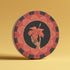 Round ceramic coaster featuring a skeleton hand holding a coral hibiscus flower, surrounded by art deco fan patterns in coral and black