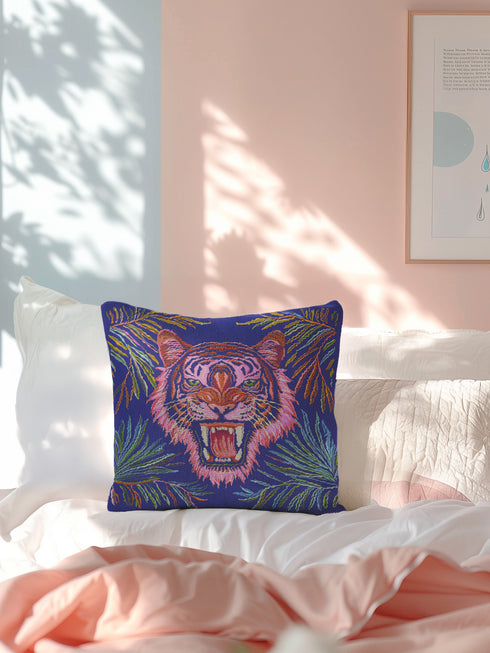 Square woven pillow featuring a fierce pink tiger with bared fangs against electric blue background surrounded by psychedelic jungle leaves. Textured tapestry design creates vibrant maximalist tiger decor perfect for gothic or eclectic home styling.
