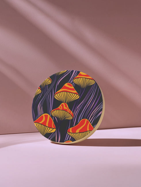 Round ceramic coaster featuring orange and yellow mushrooms with striped caps against a dark background with flowing purple lines in a psychedelic 70s style