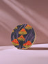 Round ceramic coaster featuring orange and yellow mushrooms with striped caps against a dark background with flowing purple lines in a psychedelic 70s style