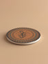 Round ceramic coaster featuring a silhouetted dancing figure reaching for a crescent moon, surrounded by concentric rings of stars and botanical patterns in terracotta and umber tones